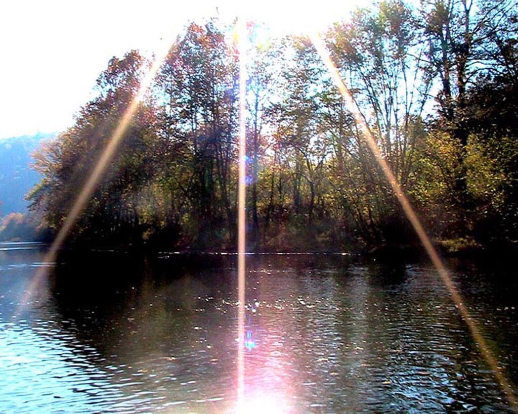 Über mich Sonnenstrahlen und Wasser mit Bäumen im Hintergrund